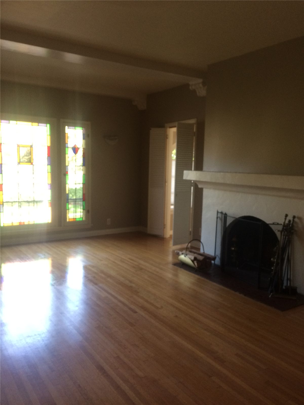 Finished living room with restored wood floors, fireplace, and decorative windows