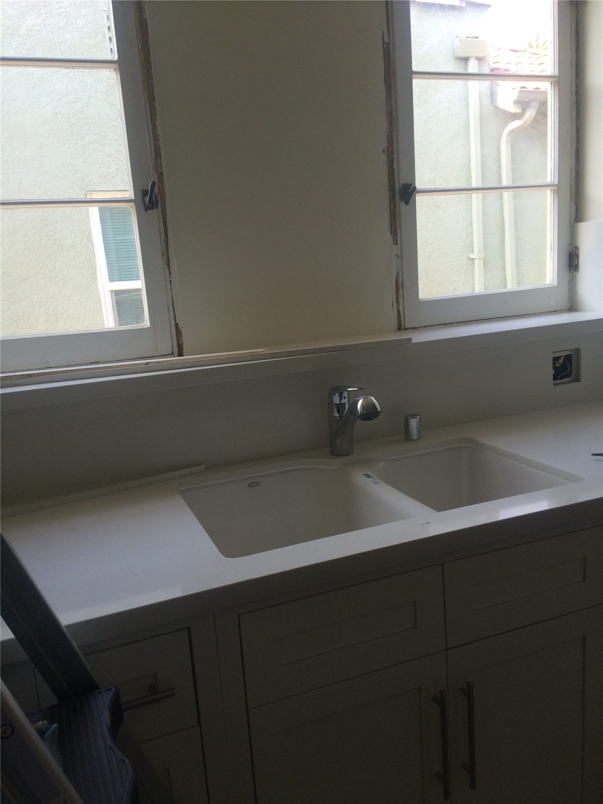 Installed kitchen sink, white counter, faucet, cabinets, and windows